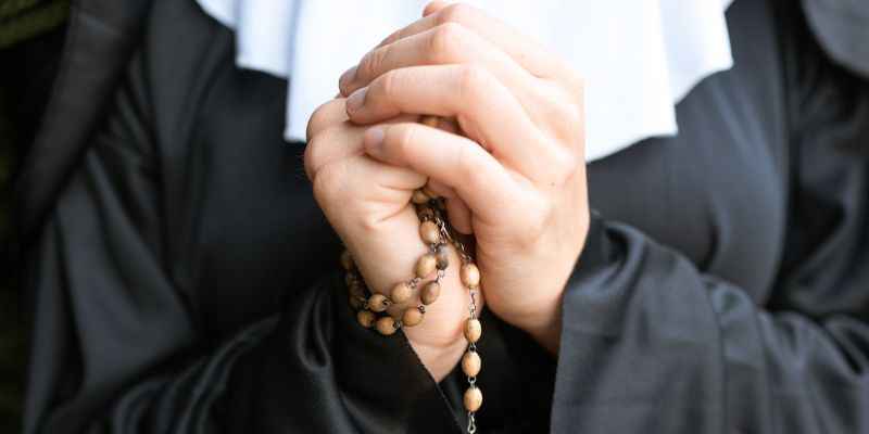A Catholic Nun and Sister Using A Rosary and Praying